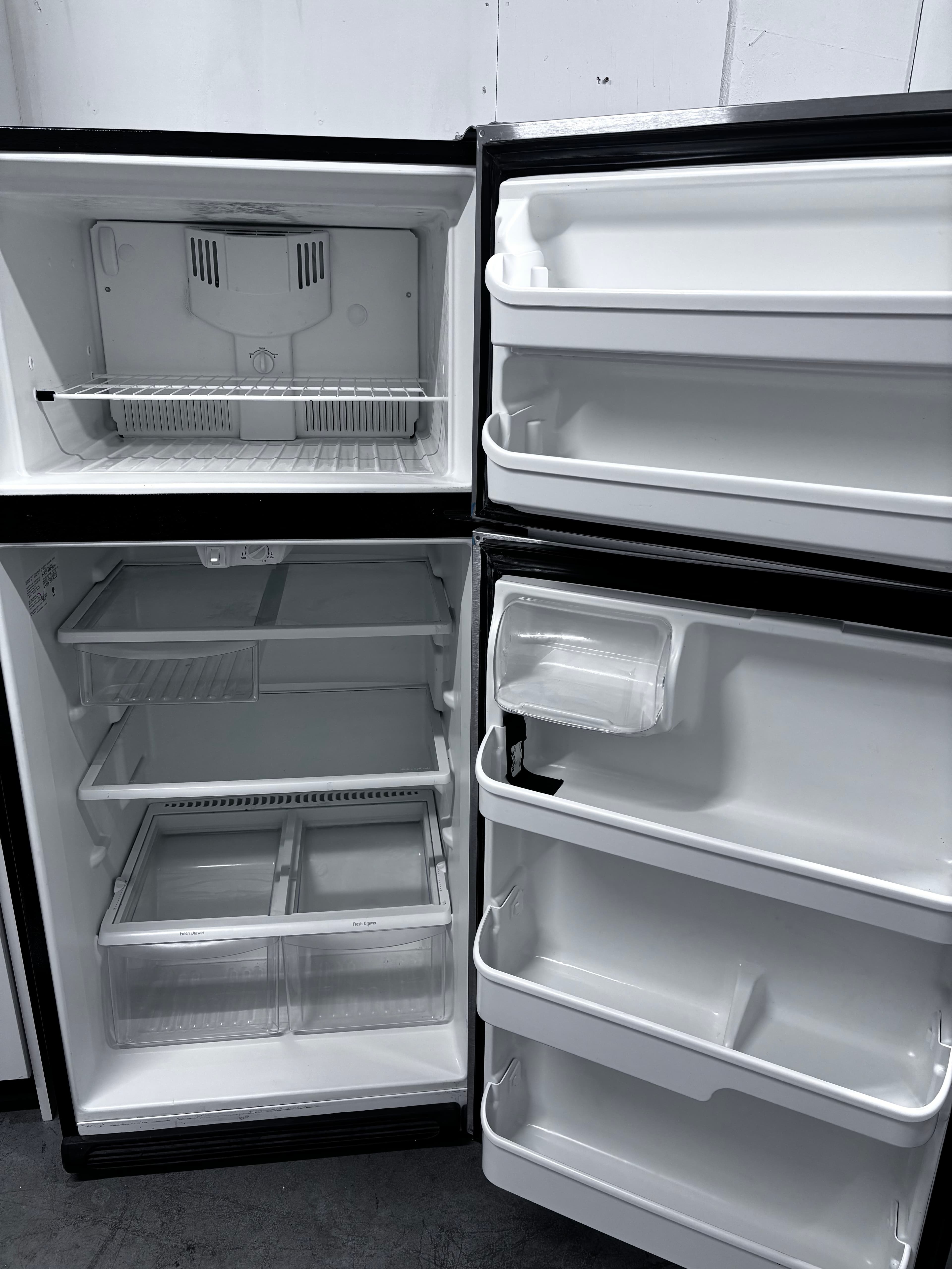 Open, empty refrigerator and freezer with cleaned shelves, drawers and door compartments.